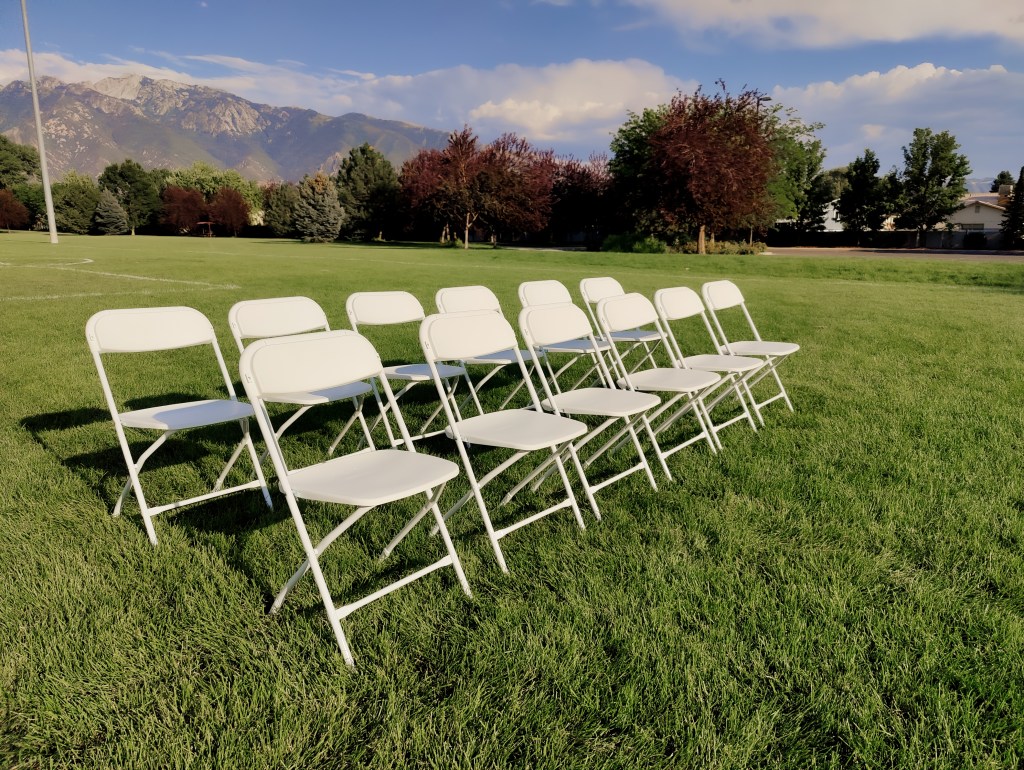 white rental chairs in field.